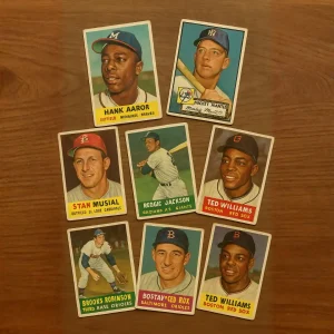 Tarjetas de béisbol vintage sobre una mesa de madera, mostrando jugadores clásicos en un diseño retro.