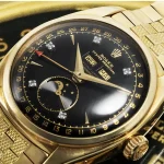 Primer plano de un reloj Rolex Reference 6062 en oro amarillo con esfera negra, calendario triple y fase lunar, acompañado de un brazalete también en oro.