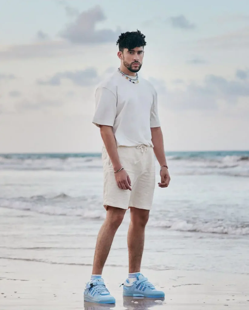 Bad Bunny usando sneakers Adidas® de edición especial en un entorno costero, imagen editorial de moda urbana y streetwear contemporáneo