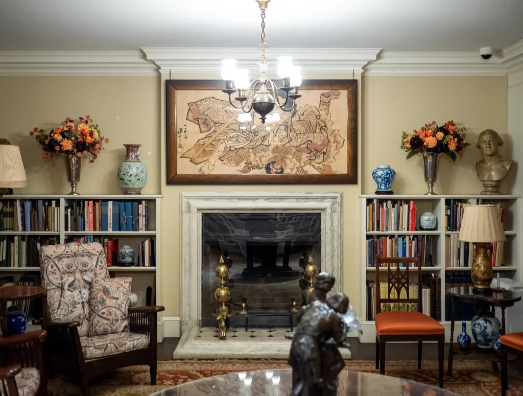 Interior del Grolier Club en Nueva York con chimenea de mármol, biblioteca clásica y estanterías con libros