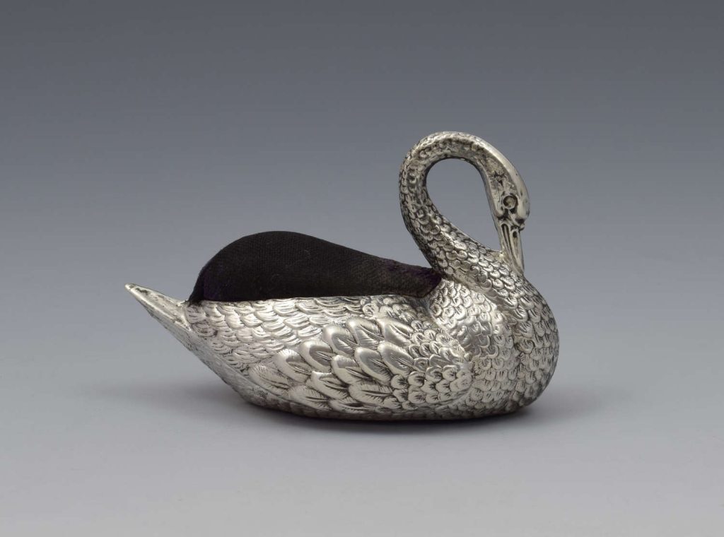 Cojín de alfileres antiguo de plata en forma de cisne con cojín superior de terciopelo oscuro, pieza victoriana coleccionable de finales del siglo XIX.