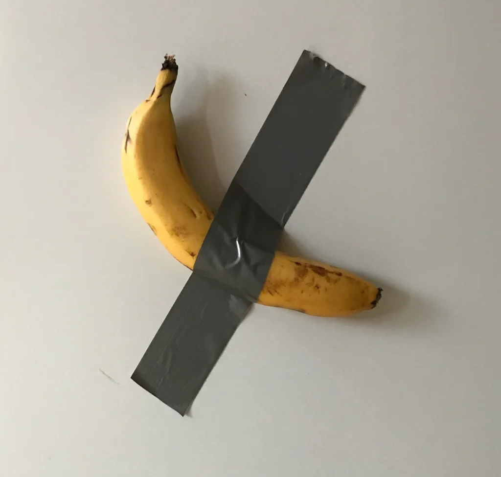 Banana adherida con cinta adhesiva a una pared blanca representando la obra conceptual Comedian de Maurizio Cattelan