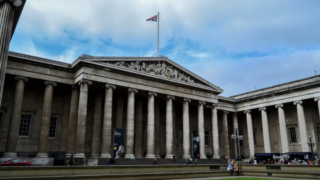 Fachada principal del British Museum en Londres con columnas clásicas y bandera del Reino Unido.