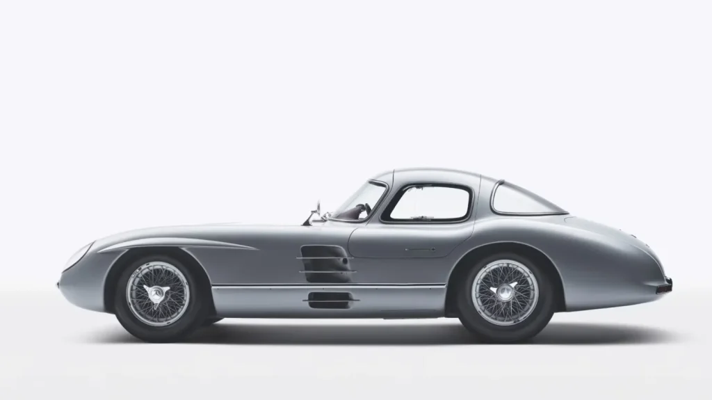 Vista lateral de perfil completo del Mercedes-Benz 300 SLR Uhlenhaut Coupé de 1955, color plateado, sobre fondo blanco aislado.